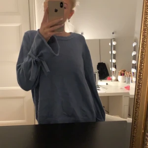 Stickad tröja - Säljer denna jättefina blåa stickade tröjan med rosetter vid ärmen från nakd. Använt få gånger och säljer för den har inte kommit till använing💕