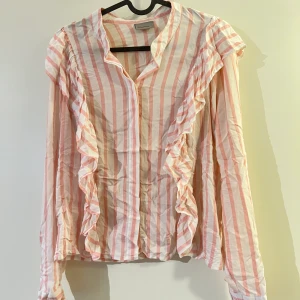 Skjorta - Rosarandig skjorta från Vero Moda i storlek S. Den är i fint skick! Volanger fram till och längst upp där bak. 