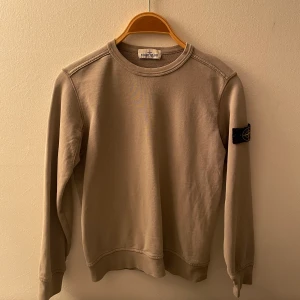 Beige Stone Island tröja  - Säljer min lillebrors kläder, kan gå i god för att allting är äkta och denna är köpt på NK. Nypris 1400 kr😊. Storleken är 142 men den är större i storleken så jag skulle säga att den passar 146/152