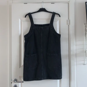 Monki Hängselklänning - Fin svart jeans hängselklänning från Monki! Den är i storlek M och har en rak/lösare passform🥰