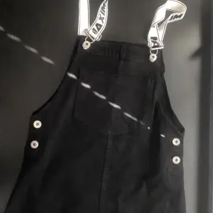 Black skirt overalls with graphic design on the white strips, buttons from the side (can be unbuttoned)