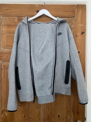 Grå Nike Tech Fleece Set - Säljer nu denna Nike Tech Fleece setet som kommer i perfekt skick inga problem och är redo till användning. Står att byxorna är i XL men sitter mer som S allstå om du är runt 170 höjden så borde den sitta utmärkt, det samma gäller med koftan. Priset går och diskuteras så kom gärna fram med bud. Fraktar samma dag som köpet genomförs ! 👌📦💨