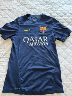 Blå FC Barcelona matchtröja Nike - Snygg blå FC Barcelona matchtröja från Nike med klubbmärke på bröstet och Qatar Airways som sponsortryck. Tröjan har korta ärmar, gul Nike-logga och är tillverkad i Dri-FIT material som andas. Perfekt för fotbollsträning eller att bära till vardags. Den är använd många gånger så det är inte det bästa skicket