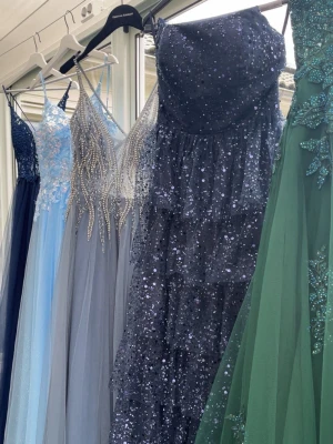 Balklänning - Säljer min superfina balklänning med tunna axelband och djup v-ringning som endast är använd en gång! Överdelen är dekorerad med glittrande pärlor och stenar som ger en lyxig känsla. Kjolen är i flera lager av tunn tyll som faller snyggt. Perfekt för studentbal! Klänningen är köpt på joahns högtidskläder för 5900 inklusive uppsydnad. Den är köpt i storlek 44 men är sydd till en 40/42❣️