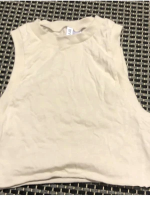 Beige ärmlös linnetopp - Säljer en enkel och stilren beige linnetopp i bomull. Toppen är ärmlös med rund halsringning och har en clean, minimalistisk look som passar perfekt till sommaren. Perfekt att matcha med jeans eller kjol för en avslappnad vibe.