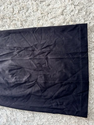 Svart kortkjol från Filippa K - En stilren svart kortkjol från Filippa K i enkel design. Kjolen har rak passform och är tillverkad i ett mjukt tyg som känns bekvämt. Perfekt att matcha med både sneakers och boots för en clean look.