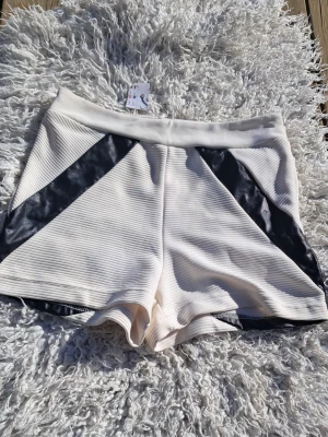 Vita shorts med svarta detaljer Amisu - Snygga vita shorts från Amisu med svarta, glansiga paneler på sidorna. Tillverkade i ribbad bomullsmix som ger en sportig känsla. Shortsens passform är norma