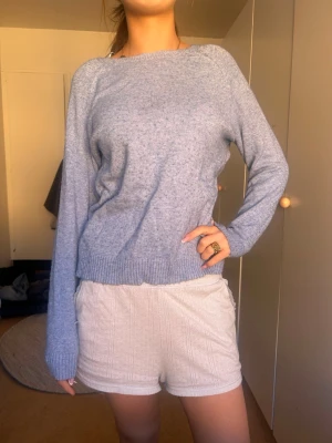 Ljusblå stickad tröja med rund hals - Mysig ljusblå stickad tröja med rund halsringning och långa ärmar. Tröjan har ribbstickade muddar vid ärmslut och nederkant. Perfekt för lager-på-lager och enkel att matcha med olika outfits.