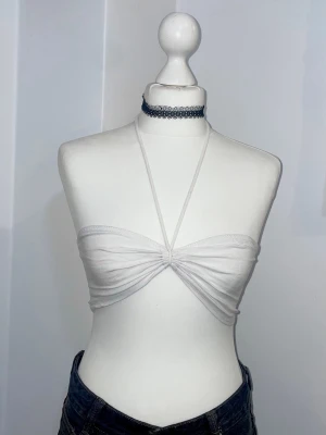 Vit bandeau tubtopp med snörning - Säljer en vit bandeau tubtopp med snörning framtill och halterneck-band. Toppen är ärmlös och har en twistad detalj i mitten. Använt en gång på festival.