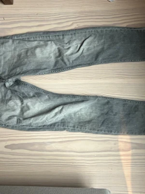 Grå jeans från Replay - Säljer ett par grå jeans från Replay med klassisk femficksdesign och knappstängning. Jeansen har en rak passform och är tillverkade i slitstarkt denim-material. Perfekta för dig som gillar en enkel och stilren look.