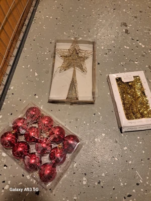 Julpynt: stjärna, kulor och glitter - Säljer ett set julpynt med en guldig trådstjärna för toppen av granen, röda julgranskulor i plast samt en förpackning med guldfärgat glitter. Perfekt för att dekorera granen och skapa julstämning hemma.