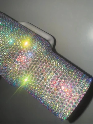 40oz Stanley glittrig mugg med sugrör - Säljer en stor Stanley-mugg med handtag och sugrör, täckt av glittrande strass i regnbågsfärger. Muggen har ett genomskinligt lock och vit plastdetalj på handtaget. Perfekt för dig som vill ha något extra bling till drycken.   (Minns inte om den vart använd en enstaka gång eller inte! Skicket är som nytt!🙌 Nyrpis: 4000kr från etsy)
