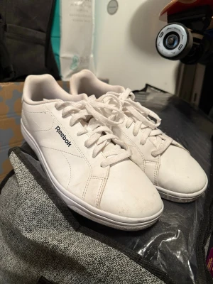  Reebok sneakers classic court clean - Säljer ett par vita Reebok sneakers med stilren design och låga skaft. Skorna har Reebok-logga på sidan och bak, vita snören och ovandel i syntetmaterial. Perfekta för dig som gillar en clean och tidlös stil.