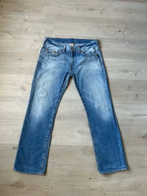 Blåa True Religion Bobby Jeans W36 - Fina True Religion Jeans i Blå färg. Jeansen är i mycket bra skick och sparsamt använda. |  Äkta som allt annat jag säljer! ✅ |  Storlek: W36 | Skick: Mycket bra skick - blivit lagade men har lite slitningar . ) | Färg: Blå | Märke: True Religion | Modell: Jeans |  Hör gärna av dig vid frågor så svarar jag så fort jag kan! 😁|   (Sku - 51)