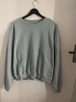 Ljusgrön oversized sweatshirt - En enkel och stilren ljusgrön sweatshirt med rund hals och ribbade muddar vid ärmslut och nederkant. Tröjan har en avslappnad, oversized passform och är tillverkad i mjukt bomullsmaterial. Perfekt för en chill och casual look. Den är normal i storlek och har en fin passform. Storlek M. 