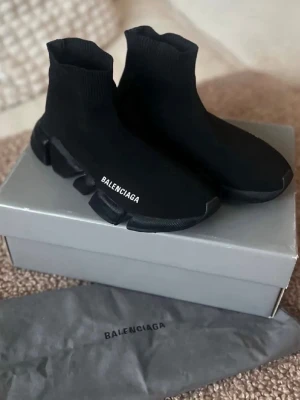 Balenciaga Speed Trainer svarta sneakers - Svarta Balenciaga Speed Trainer sneakers med strumpliknande ovandel i stretchigt tyg och chunky sula. Diskret Balenciaga-logga på sidan. Snygg och futuristisk design som sticker ut. Perfekta för dig som gillar streetwear och vill ha något unikt.