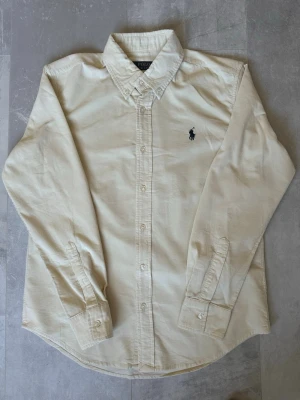 Skjorta från Polo Ralph Lauren - Säljer en klassisk beige skjorta från Polo Ralph Lauren. Perfekt för dig som gillar stilrena plagg. Riktig skön och lyxig skjorta för våren samt sommaren. Storlek M