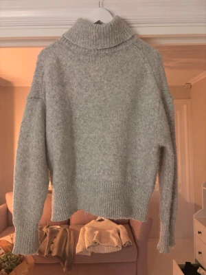 Grå polotröja  - Mysig grå polotröja med bred ribbad krage och långa ärmar. Perfekt för kyliga dagar och har en loose passform som ger en chill vibe.