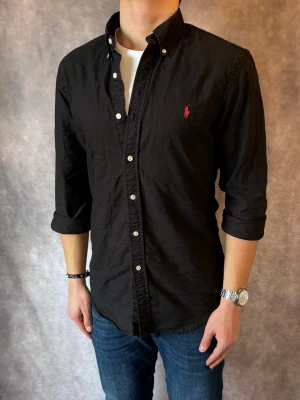 Svart Ralph Lauren Skjorta - Stl M, Slim Fit - RIKTIGT FET RL SKJORTA I FÄRGEN SVART, perfekt till sommaren som närmar sig! 🏖️🌊 |Mycket bra skick: 9,5/10, utan defekter! | Stl: M |  Modellen är 176cm och väger 75kg,  | Hör av dig vid frågor // Galgen 🫡