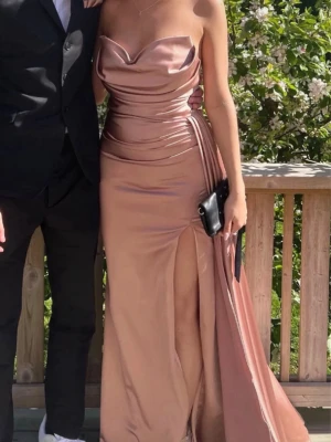 Champagnefärgad långklänning i satin - Snygg långklänning i champagnefärgad satin. Köpt på plick men använt en gång av mig. Har tecken på användning men är i fint skick🫶Jag är 170 cm lång och bör ca 7cm klackar på bilden 