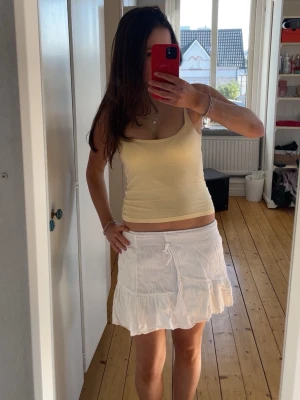 Vit volangkjol med snörning - Jättefin low waist kort vit kjol i barn storlek men passar som xs! Perfekt till sommaren, har inga fläckar och säljer då den inte kommer till användning💞💞