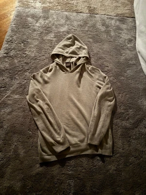 Beige hoodie från Oscar Jacobson - Säljer en stilren beige hoodie från Oscar Jacobson. Hoodien har en klassisk huva och är tillverkad i ett mjukt, tunt material som känns lyxigt. Perfekt för dig som gillar en clean och enkel look med premiumkänsla.