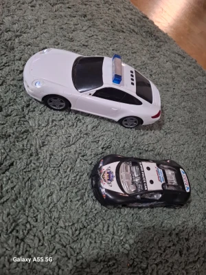 Två leksaksbilar i plast - Säljer två leksaksbilar i plast, en vit polisbil med blå detaljer och en svart racerbil med dekaler. Perfekta för bilälskare som gillar att leka på mattan eller samla på bilar. Båda bilarna har sportig design och rullande hjul.