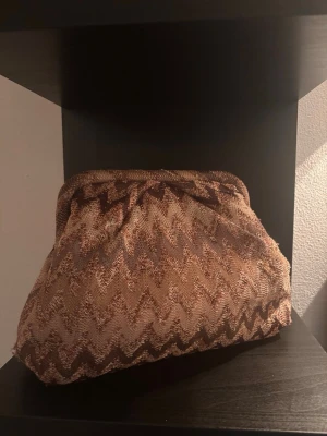 Eftertraktad Beck Söndergaard clutch  - Säljer den eftertraktade clutchen från Beck Söndergaard. Jättefin clutch/väska, tyvärr har den fått några hål men jag tänker inte på det när jag använder den. Hålen är i samma färg så det syns inget. Annars är det inga defekter på den. Säljer endast för en bra summa. Lägg gärna ett bud. 