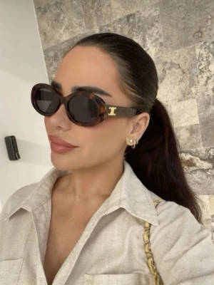 Bruna ovala solglasögon från Celine - Säljer ett par trendiga solglasögon från Celine med oval form och bred båge i brunsköldpaddsmönster. Glasögonen har guldfärgade Celine-loggor på sidorna och mörka linser. Perfekta för att lyfta vilken outfit som helst.