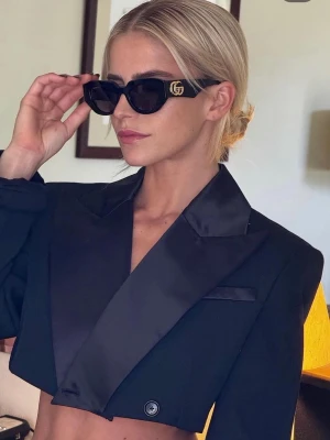 Svarta solglasögon från Gucci - Snygga svarta solglasögon från Gucci med markerad, kantig båge och guldfärgad GG-logga på sidan. Glasen är mörka och bågarna är tillverkade i blank syntet. Perfekta för att lyfta vilken outfit som helst.