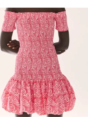 SÖKER, SKRIV IFALL DU HAR OCH KAN SÄLJA INOM 300-400kr - Söt rosa kortklänning med offshoulder och volangkant. Klänningen har ett mönster i vitt och rosa, smockad överdel och puffig kjol. Perfekt för dig som gillar färg och lekfull stil.
