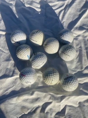 10 vita golfbollar blandade märken - Säljer ett set med 10 vita golfbollar från olika märken. Bollarna har klassisk rund form och är tillverkade i slitstarkt material med dimple-mönster för bättre flygförmåga. Perfekt för dig som vill fylla på golfbagen med extra bollar.