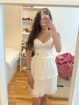 Student klänning, Vit plisserad klänning Chiara Forthi - Superfin vit klänning från Chiara Forthi med plisserad kjol och dubbla lager. Klänningen har en elegant, figurnära överdel och är tillverkad i ett glansigt material som ger en lyxig känsla. Perfekt för dig som vill sticka ut med en stilren look.
