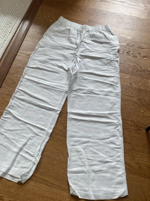 Vita linnebyxor med resårmidja H&M - Snygga och luftiga vita linnebyxor från H&M med rak passform och resår i midjan. Byxorna är tillverkade i en linnemix som gör dem perfekta för varma dagar. Passar mig som är 177 cm lång.
