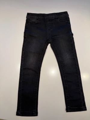 Svarta skinny jeans från Kappahl - Snygga svarta skinny jeans från Kappahl med klassisk femficksdesign och stretchigt material. Jeansen har smal passform och normal midja, perfekta till en avslappnad streetstyle-look.