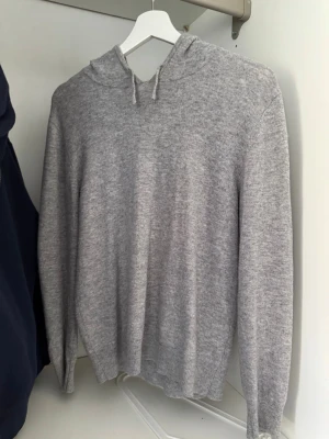Grå Kashmir hoodie - En stilren ljusgrå kashmir hoodie med huva och dragsnören. Tillverkad i ett mjukt kashmir tyg.  Passar xs. Pris kan diskuteras