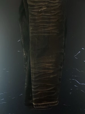 Svarta Amiri byxor med slitningar - Coola svarta amiri byxor  med tydliga slitningar och stora fickor på sidorna. Byxorna har en avslappnad passform och är perfekta för en streetwear-look. Materialet ser ut att vara denim eller bomullsblandning. endast använd några få gånger