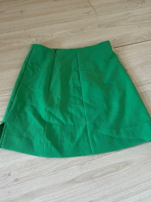 Grön kjol  - Grön kjol från cubus, storlek xs men passar s även. Slits på kanten längst ned och har en dragkedja. Använd 1 gång när jag provade den, hel och fin. Prislappen är kvar , köpt för 349 kr säljer för 30