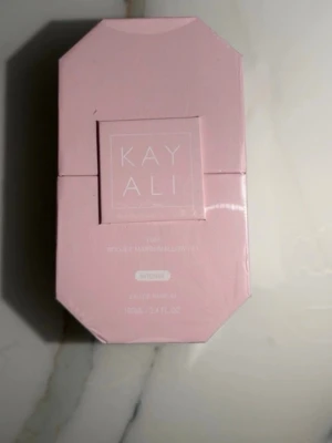 Kayali Yum boujee Marshmallow 100ml - Kayali Yum Pistachio marshmallow i en snygg ljusrosa, åttakantig förpackning. Doften har inslag av pistage och marshmallow och flaskan rymmer 100 ml. Perfekt för dig som gillar söta och unika parfymer.