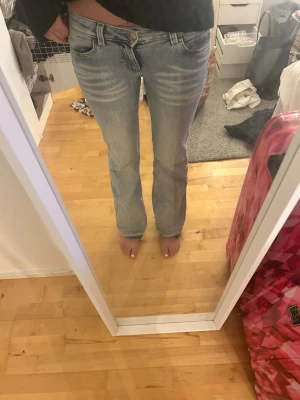 Ljusblå bootcut jeans med slitningar - Säljer ett par ljusblå bootcut jeans med snygga slitningar och tvättade detaljer framtill. Jag har sprättat benen så att det ska bli längre och en liten cool detalj med det mörkblåa 😊