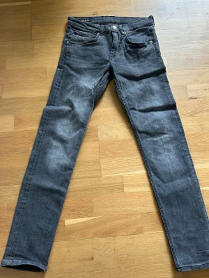 Grå slim fit jeans från J.Lindeberg - Snygga grå slim fit jeans från J.Lindeberg med klassisk femficksdesign och dragkedjegylf. Jeansen har en tvättad look och raka ben, perfekta för en stilren och modern outfit.