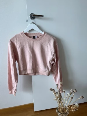 Ljusrosa cropped sweatshirt  - Säljer en ljusrosa cropped sweatshirt från H&M Divided. Tröjan har rund halsringning, långa ärmar och ribbade muddar vid hals och ärmslut. Perfekt för en avslappnad och trendig look. Tillverkad i mjukt bomullsmaterial.