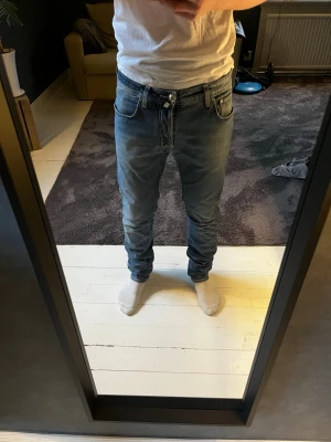 Blå Jacob cohën jeans  - Säljer ett par blå jacob cohën jeans med klassiska fem fickor och vita kontrastsömmar. Den har ett hål som man ser på bild 7 men syns inte när man har på sig dem. Modellen är 177 cm och väger 62 kg. Storlek 32, hör av er om ni har några frågor!☺️