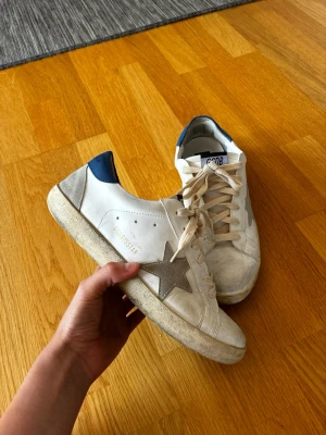 Golden Goose vita sneakers med blå detalj - Säljer ett par feta Golden Goose skor ⭐️ Säljer pga dom har blivit för små. Kontakta gärna för mer information eller bilder. Kan gå ner i pris vid snabb affär 💫