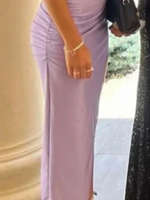 Ljuslila långklänning med slits - Säljer en elegant ljuslila långklänning med hög slits på sidan och figurnära passform. Klänningen har rynkade detaljer längs sidorna och är tillverkad i ett mjukt, stretchigt material som ger en smickrande siluett. Perfekt för dig som vill sticka ut!