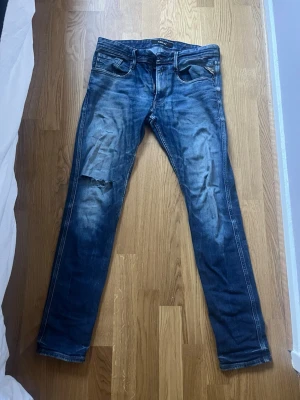 Replay slim fit, slitna jeans med hål - Säljer ett par blå replay slim fit jeans med slitningar och ett hål på vänster lår. Jeansen har klassisk femficksmodell och snygg tvättad
