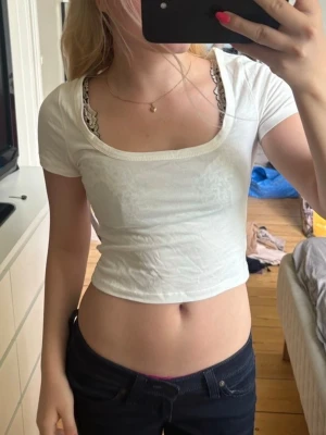 Vit croppad t-shirt  - Säljer en helt ny vit croppad t-shirt från Nelly med rundad, djup urringning och korta ärmar. T-shirten är i mjuk bomull och har en tight passform som framhäver midjan🧘🏼‍♀️🤍✨