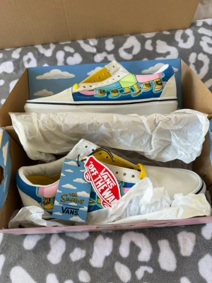Nya Vans x Simpsons  sneakers - Unika sneakers från Vans i samarbete med The Simpsons. Nya med prislapp. Skorna har en färgglad design med motiv av Simpsons-familjens ben, vita partier, gula skosnören och detaljer i blått, rosa och grönt. Klassisk låg modell med vit sula och canvasmaterial. 