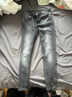 Svarta skinny jeans med dragkedja - Snygga svarta skinny jeans med slitna detaljer och dragkedja vid benslut. Jeansen har klassisk femficksdesign och är tillverkade i 98% bomull och 2% elastan för en skön stretchig känsla.