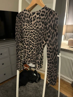 Leopardmönstrad långärmad topp - Snygg långärmad topp med leopardmönster i svart och beige toner. Figurnära passform och rund halsringning. Perfekt för dig som vill sticka ut med en trendig look.